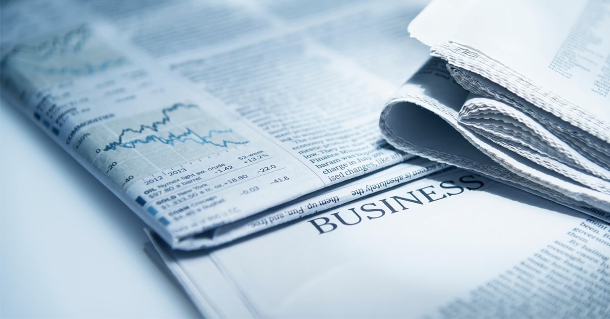 A pile of newspapers that specifically show the business section with graphs and related articles.