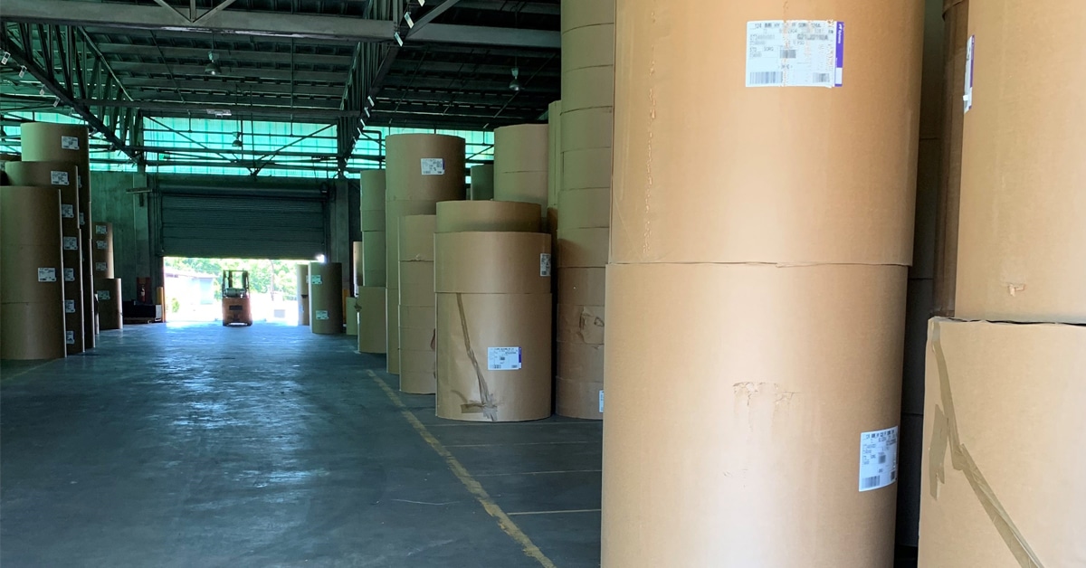 An RSI Rail Transloading Warehouse with rolls of material and a distant forklift.