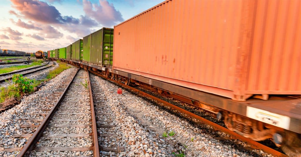 Orange and green railcars along a track.