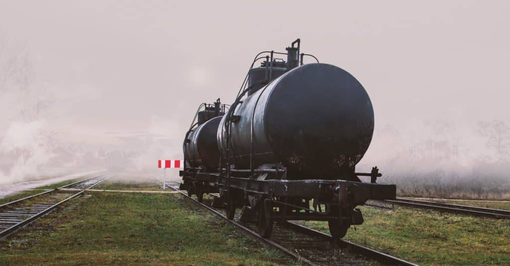A tank car on a track in front of a bank of white fog.