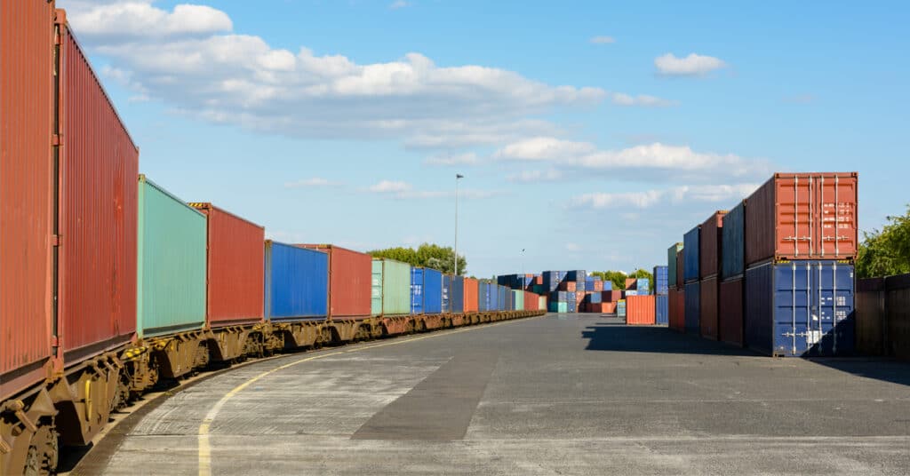 A freight train loaded with intermodal cargo containers stationed at a rail terminal.