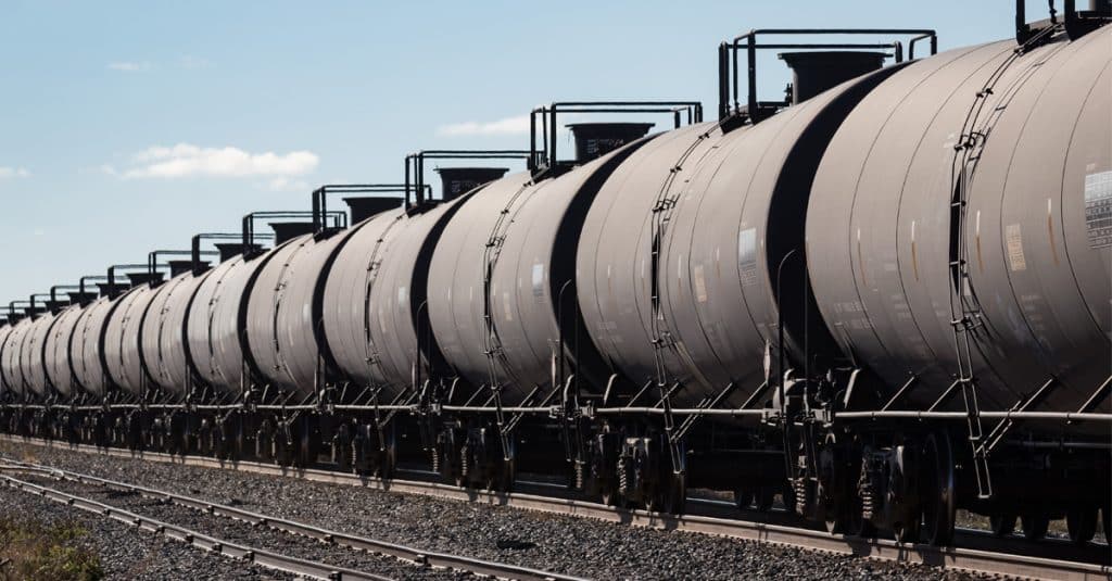 Line of black tank cars under a blue sky.