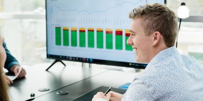 One of RSI's rail experts smiling while speaking across a table in front of a graph showing monthly rail trends.
