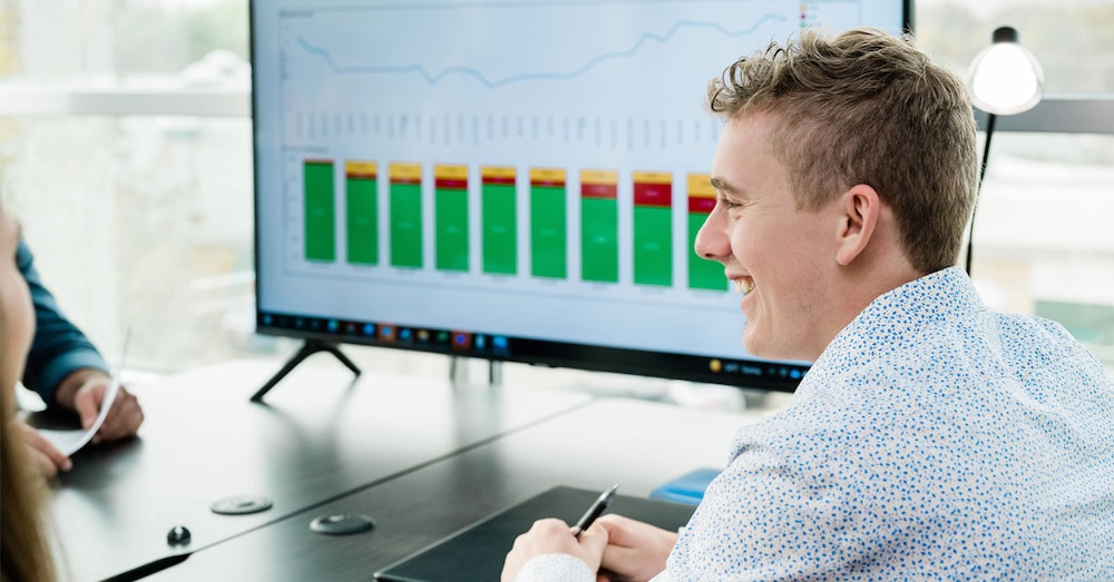 One of RSI's rail experts smiling while speaking across a table in front of a graph showing monthly rail trends.