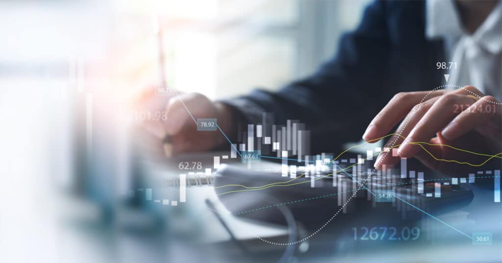 A business person uses a calculator while numbers and a trend graph is displayed atop.
