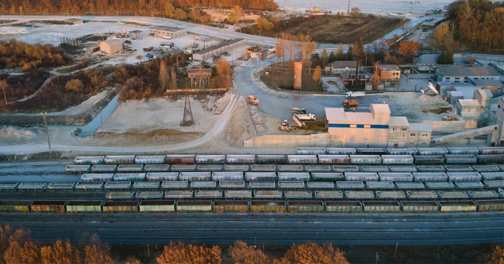 Aerial view of lines of cargo trains loaded with crushed stone materials at mining factory.