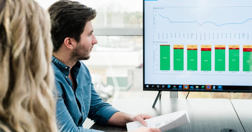 An RSI Logistics rail logistics professional looks at a colorful line and bar graph displayed on a screen.