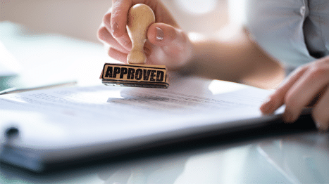 Contract and woman stamping the document with an Approved stamp.